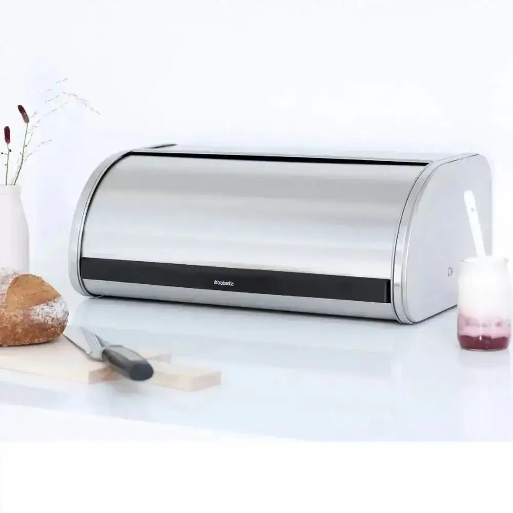 Silver bread bin on a white surface with kitchen items around