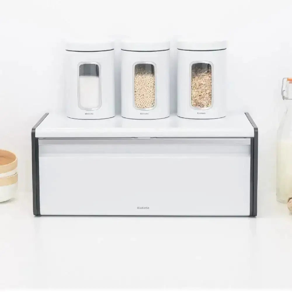 Set of three white canisters with clear lids on a white surface