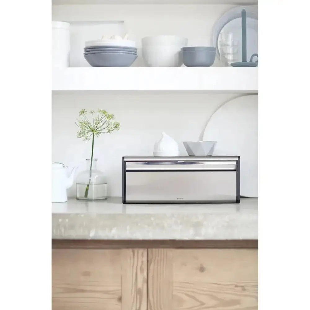 Modern kitchen setup with a bread bin on a countertop, white cabinets, and decorative items.