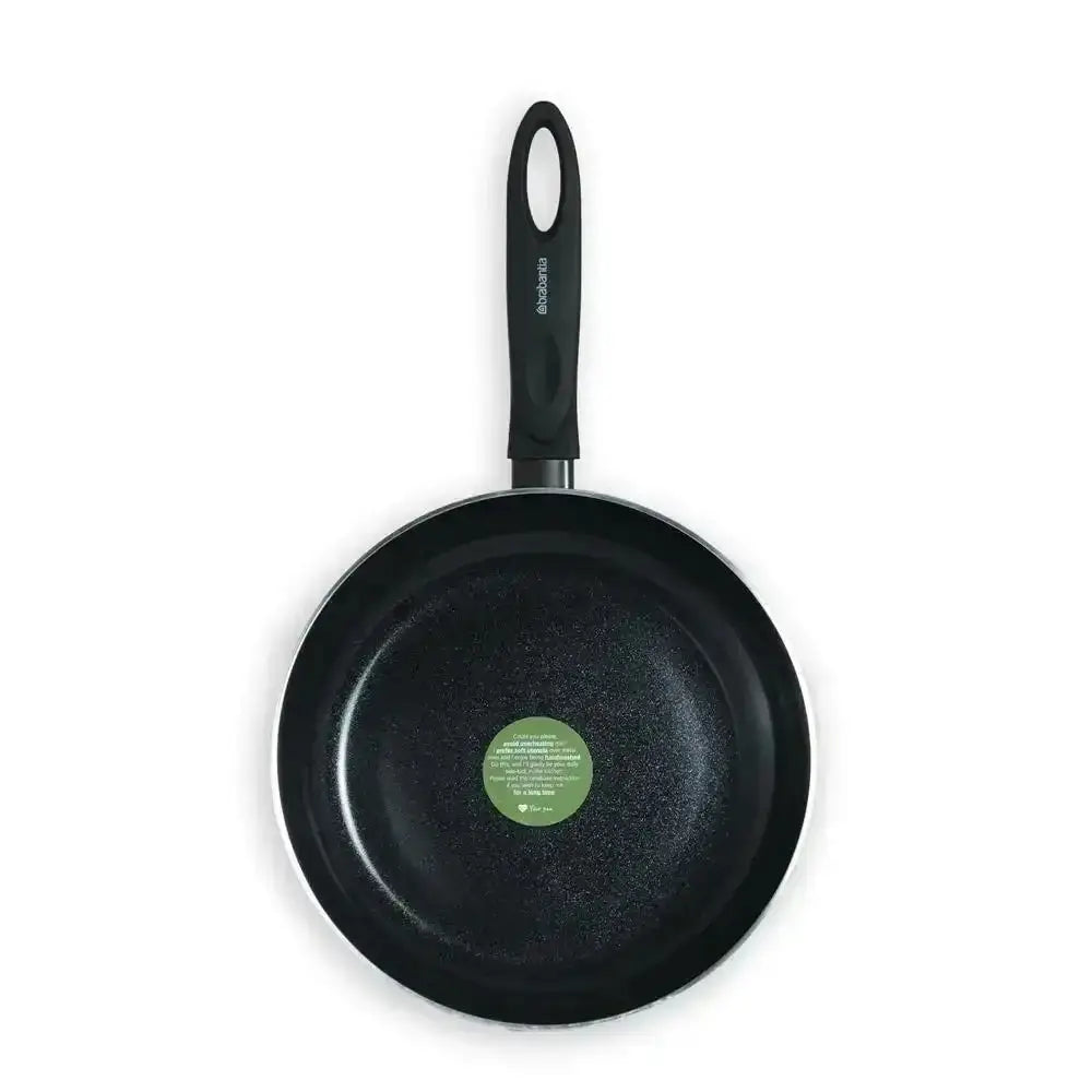 Black frying pan with a green label on a white background