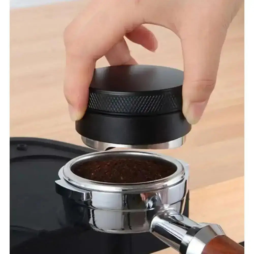 Hand using a coffee tamp to compress coffee grounds into a portafilter basket.