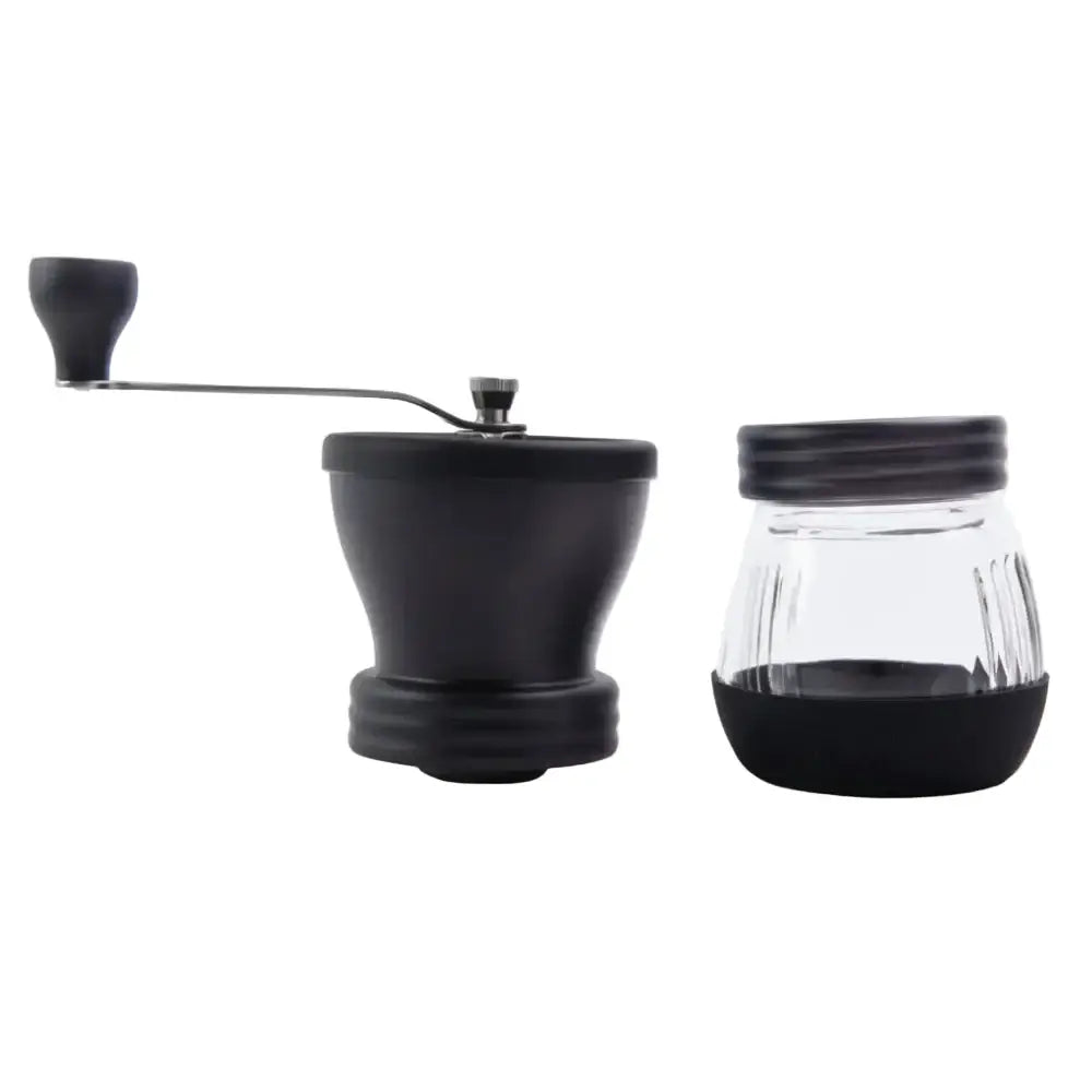 Black manual coffee grinder and glass container on a white background