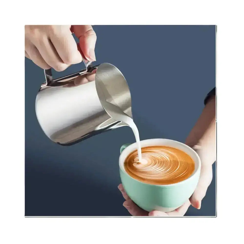 Stainless steel milk frothing jug pouring steamed milk into latte art coffee cup