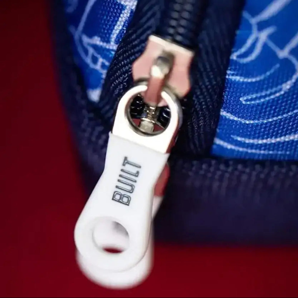 Close-up of a white zipper pull with 'BUILT' branding on a blue background.