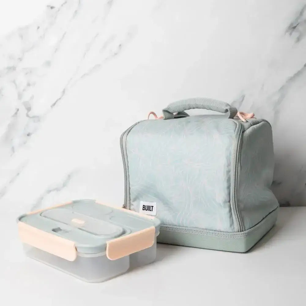 Light blue insulated lunch bag with a matching container on a marble surface