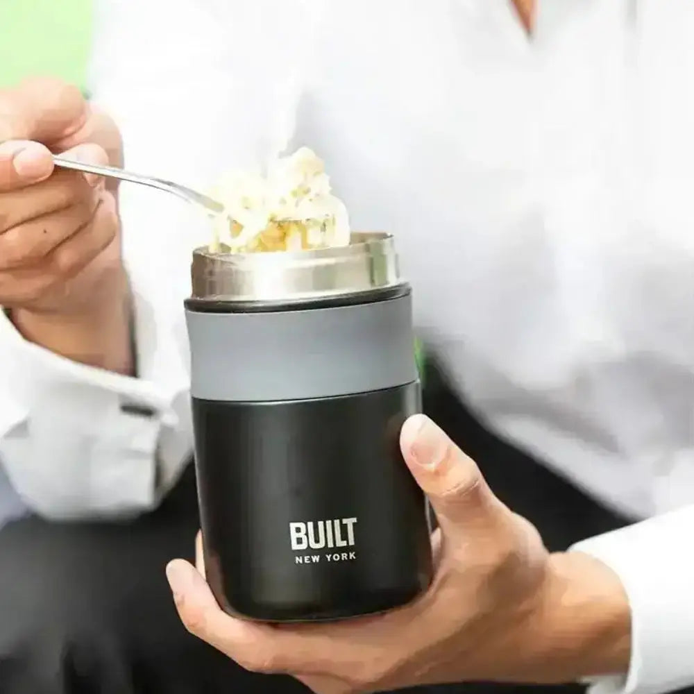 Person holding a Built New York insulated food container with a spoonful of dessert.