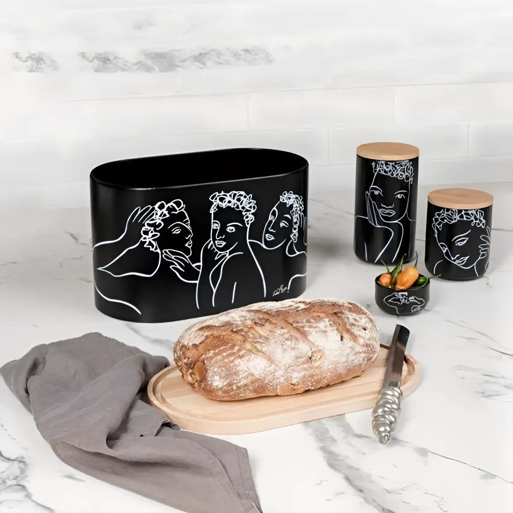 Black ceramic container with artistic designs on a marble surface with bread and a knife.
