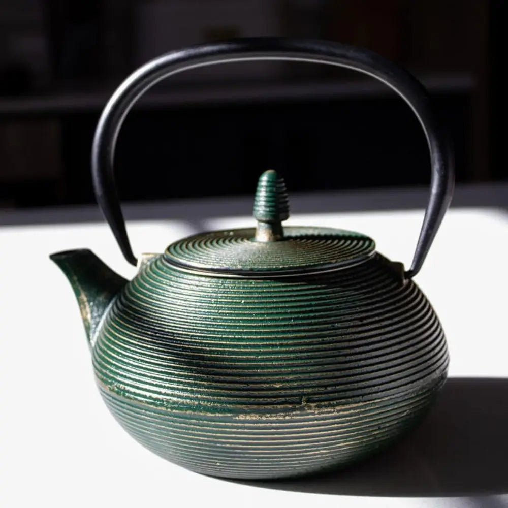 Green ceramic teapot with ribbed design on a dark background