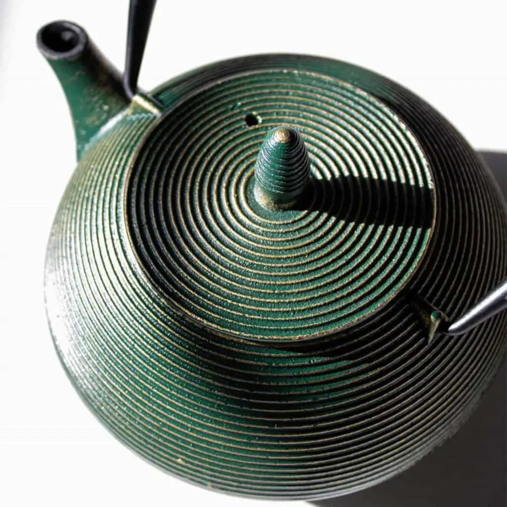 Close-up of a green ceramic teapot with a textured surface