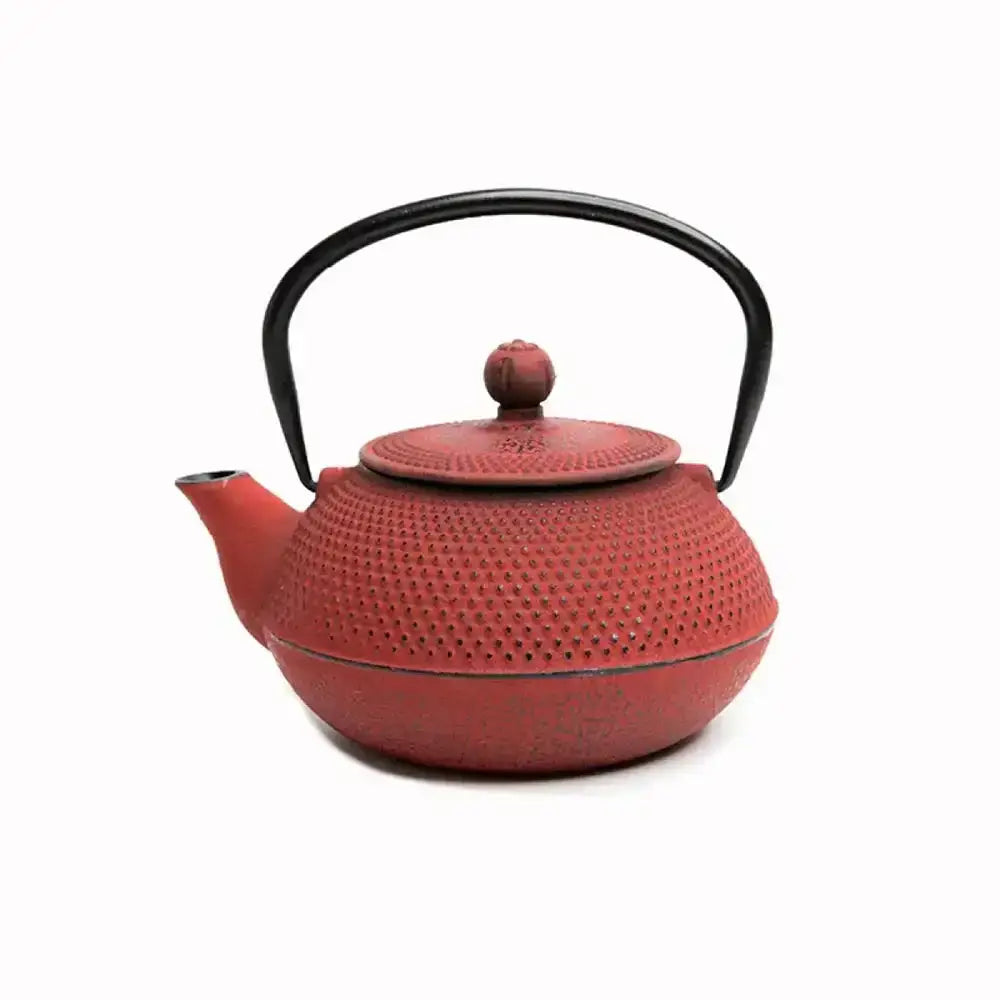 Red cast iron teapot with black handle on a white background