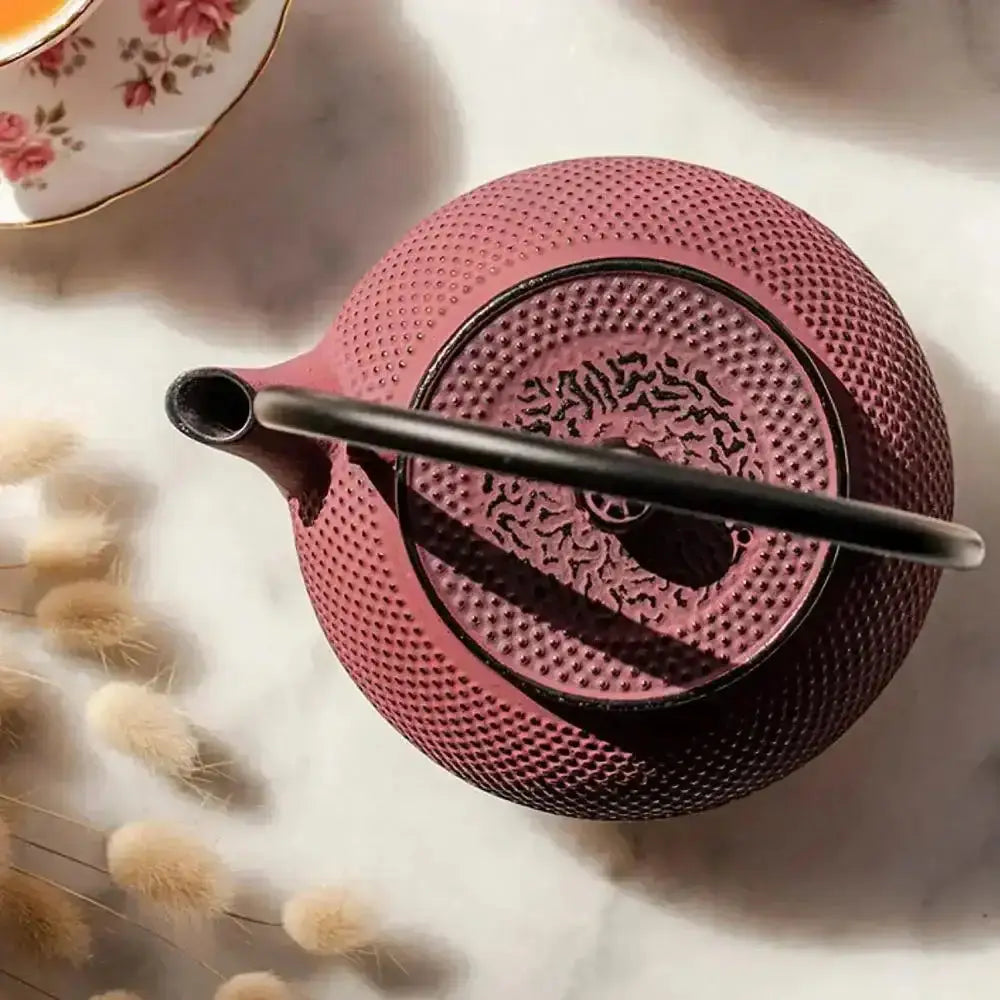 Red textured teapot with black handle on a light background