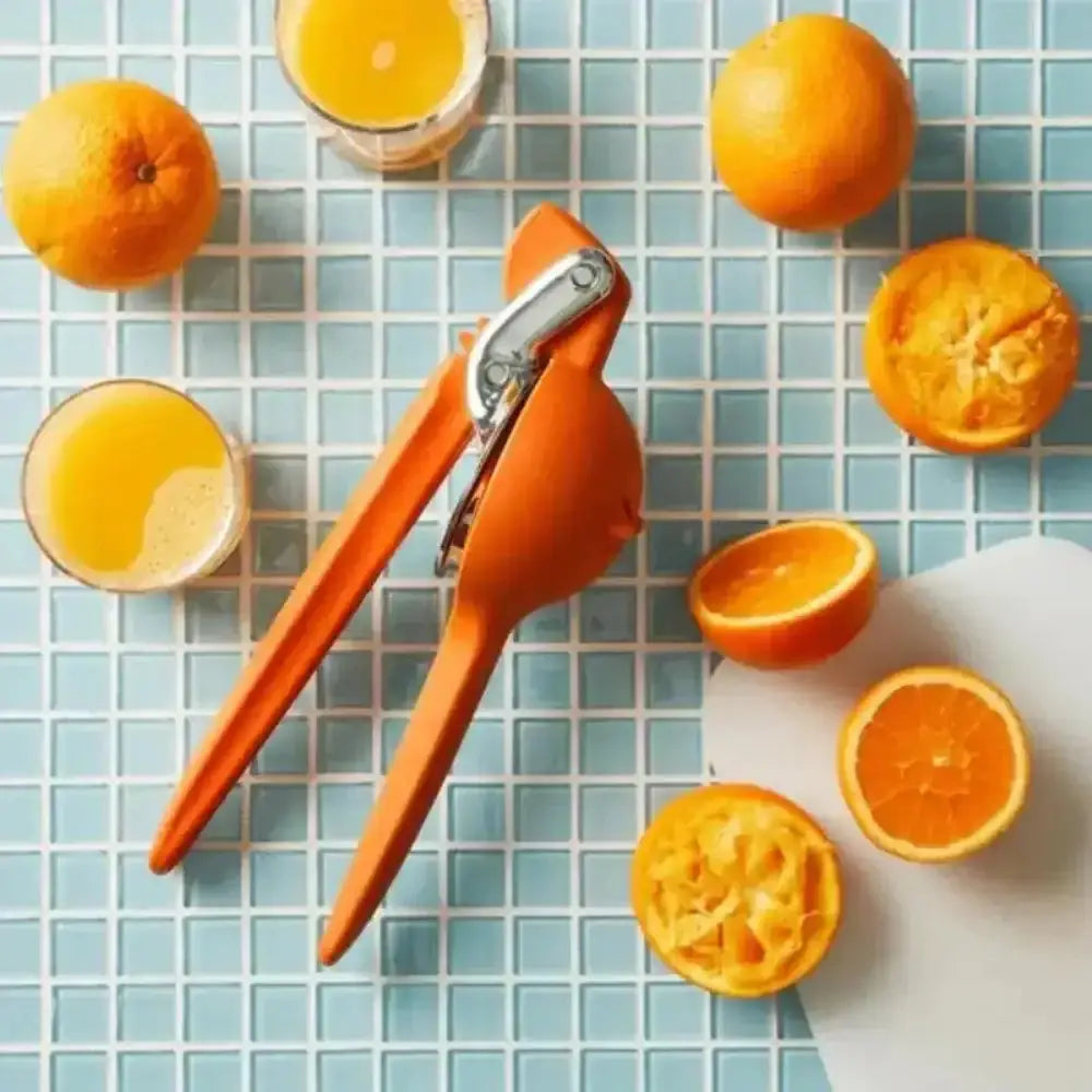 Orange manual juicer with oranges and juice on a tiled surface