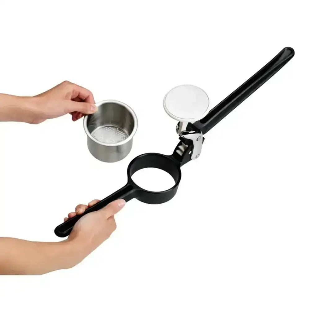 Hand holding a black potato ricer with a metal container on a white background.
