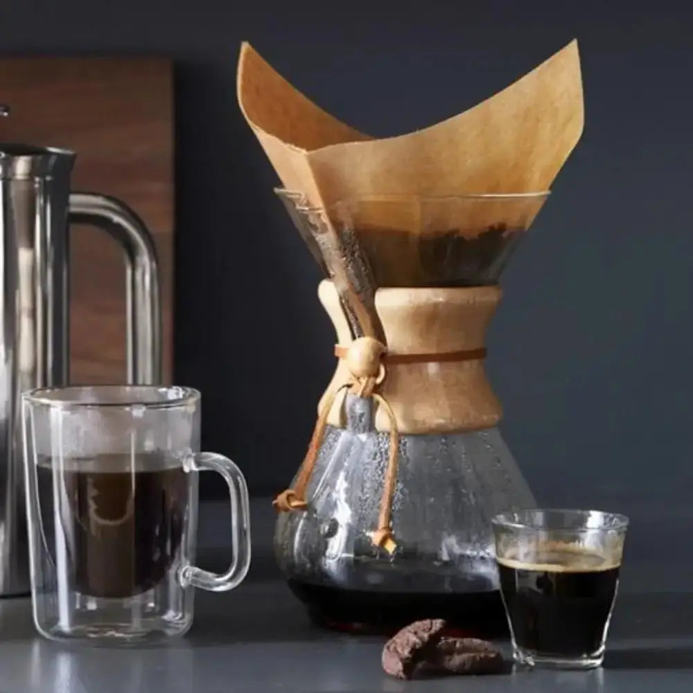 Wooden coffee dripper with two glasses of coffee on a dark surface