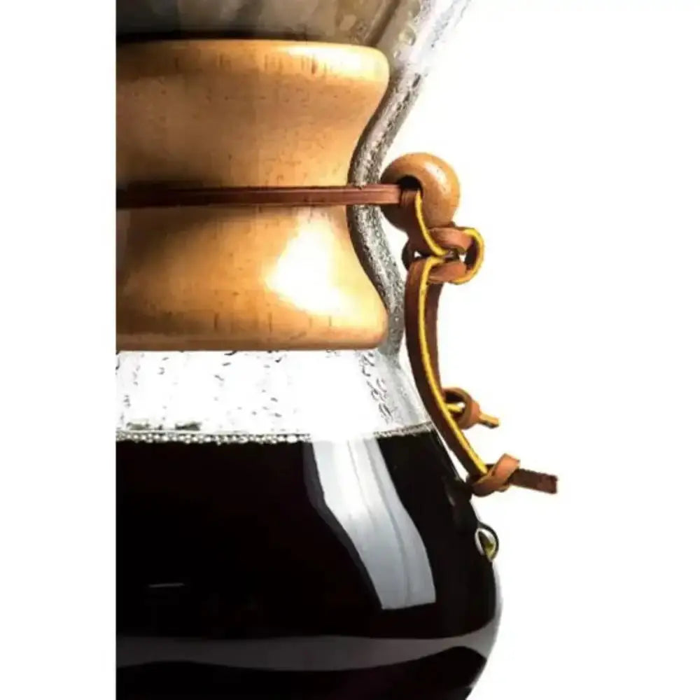 Close-up of a bronze and glass coffee maker with coffee being brewed.