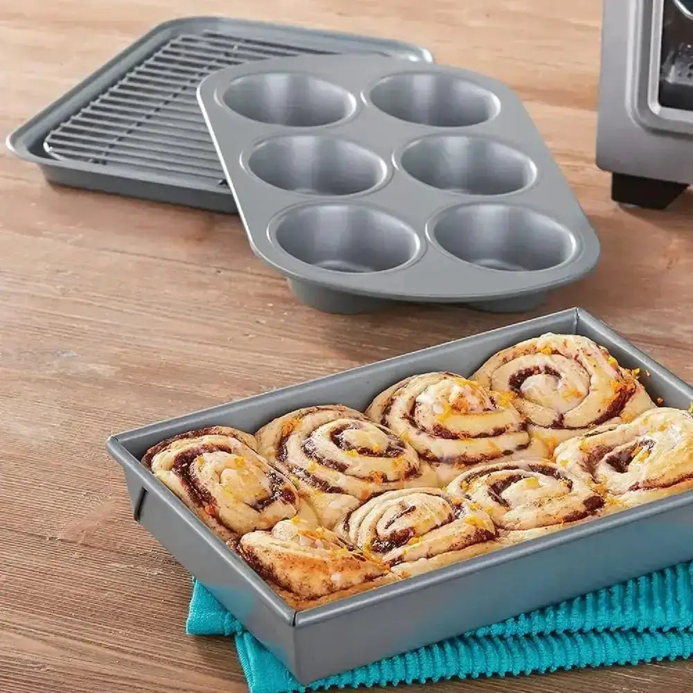 Chicago Metallic non-stick bakeware set with cinnamon rolls, muffin pan, cooling rack on wood table