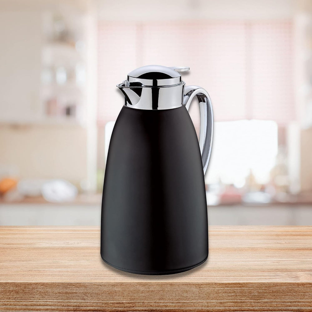 Black thermos carafe with silver lid on a wooden surface in a kitchen setting