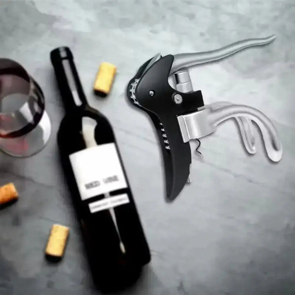 Wine bottle, corkscrew, and wine glass on a gray surface