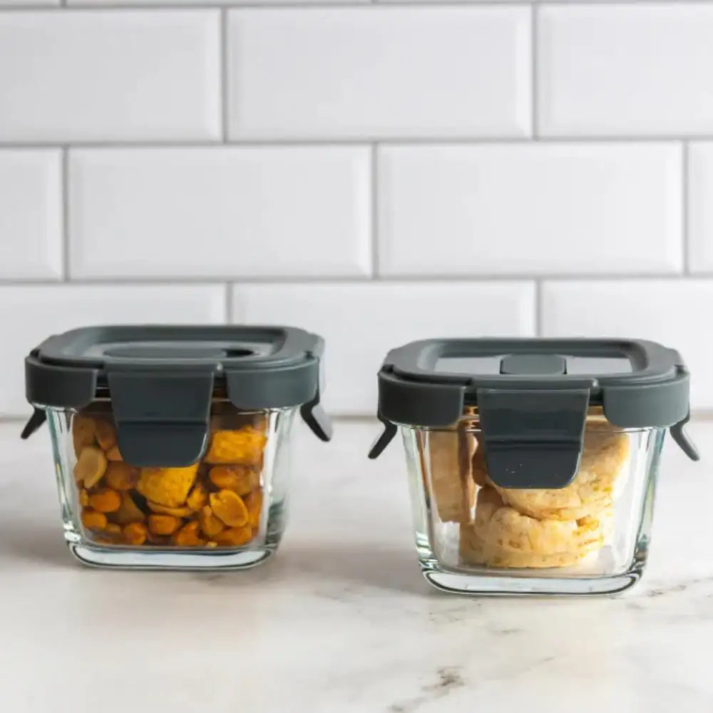 Two glass containers with black lids on a kitchen counter.