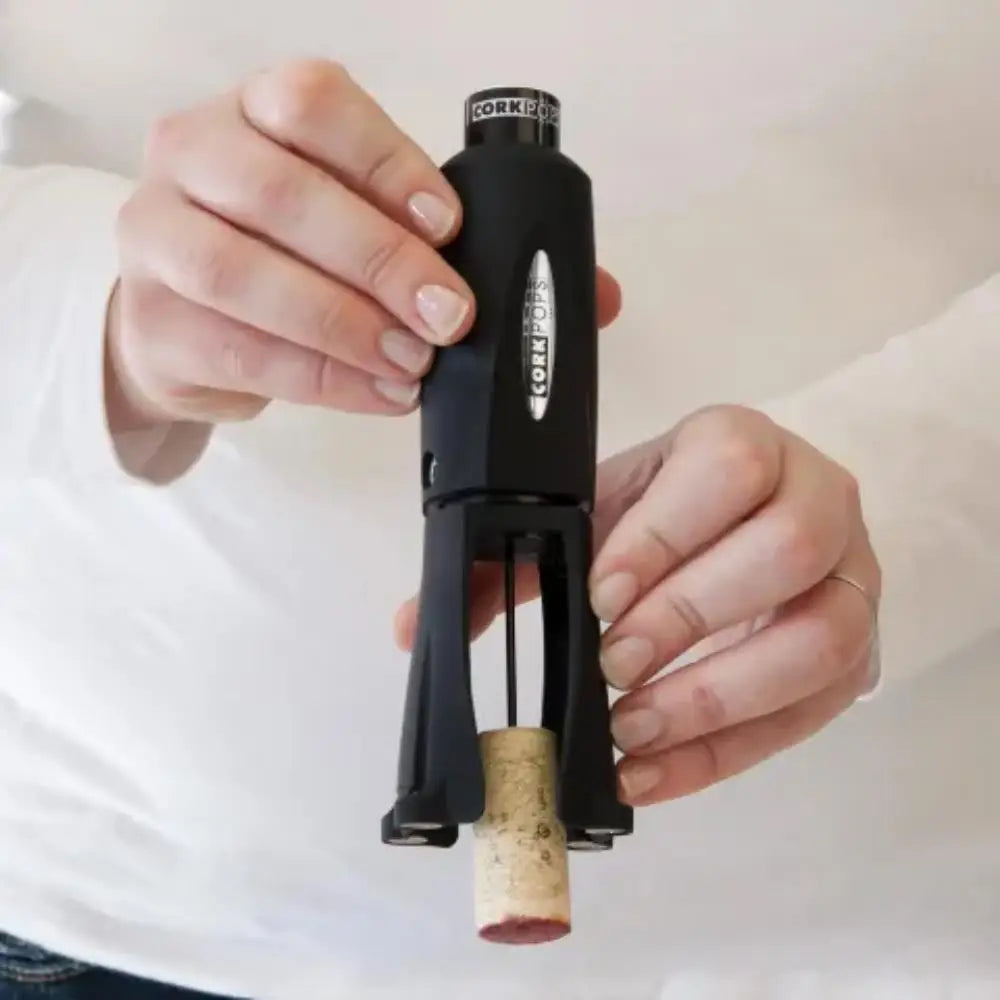 Person using a black corkscrew to remove a cork from a bottle.