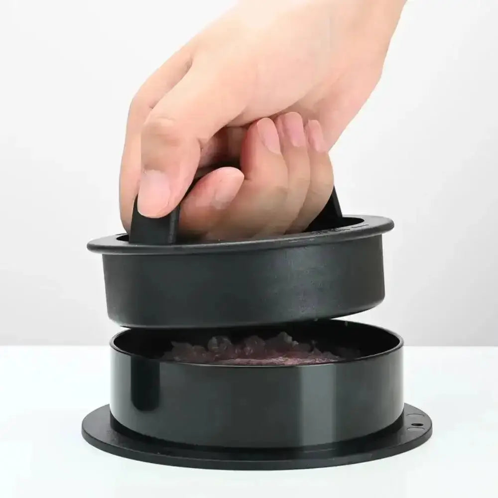 Black kitchen tool with a handle being used to crush something, on a white background