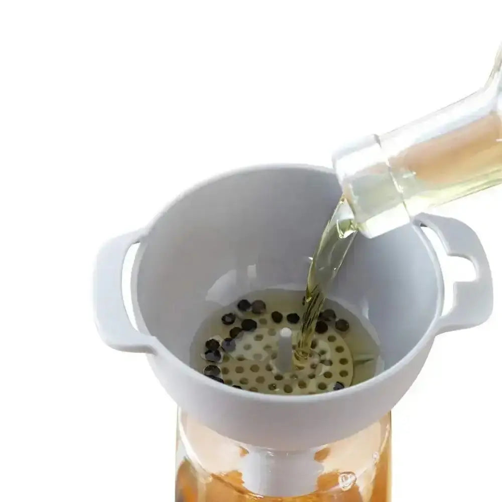 White colander with berries being poured into it from a bottle on a white background