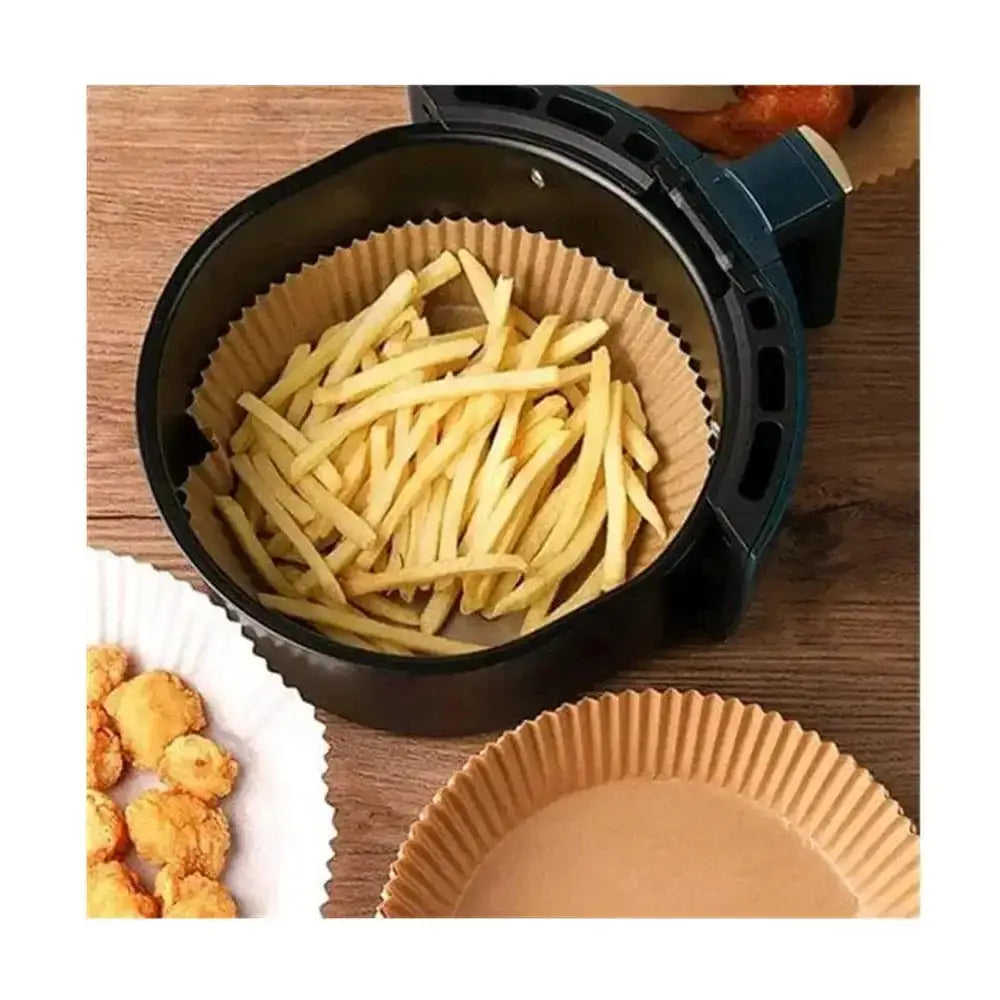 Air fryer basket with French fries and paper cups on a wooden surface