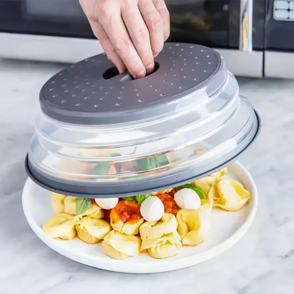Collapsible food cover being placed over a plate of pasta with a hand holding the top.