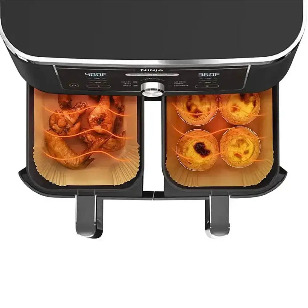 Ninja foodi appliance with food items on paper trays on a white background