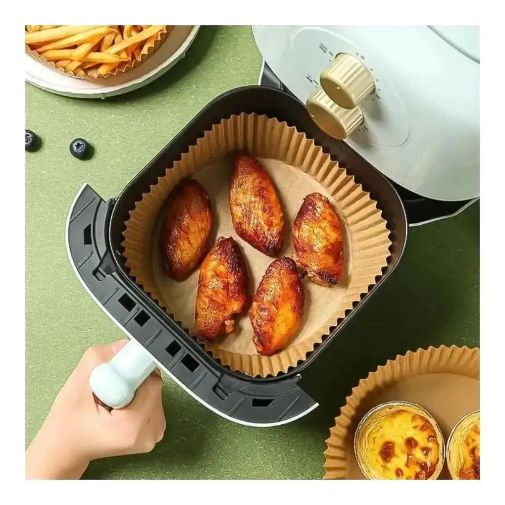 Person using a portable grill with chicken wings on a green surface