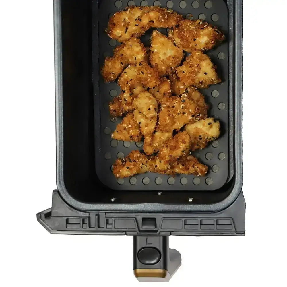 Air fryer basket with crispy chicken pieces on a white background