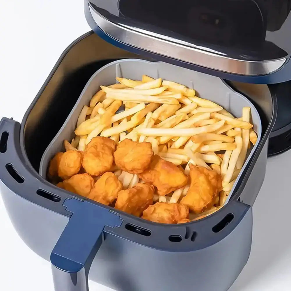 Air fryer basket with French fries and chicken nuggets on a white background