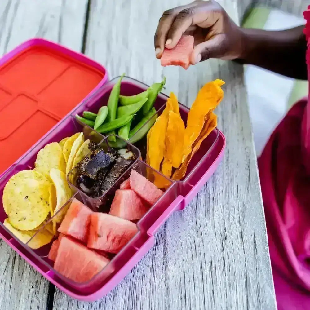 Crunchbox Classic pink lunchbox with assorted snacks and fruit on wooden table at Cookin Stores