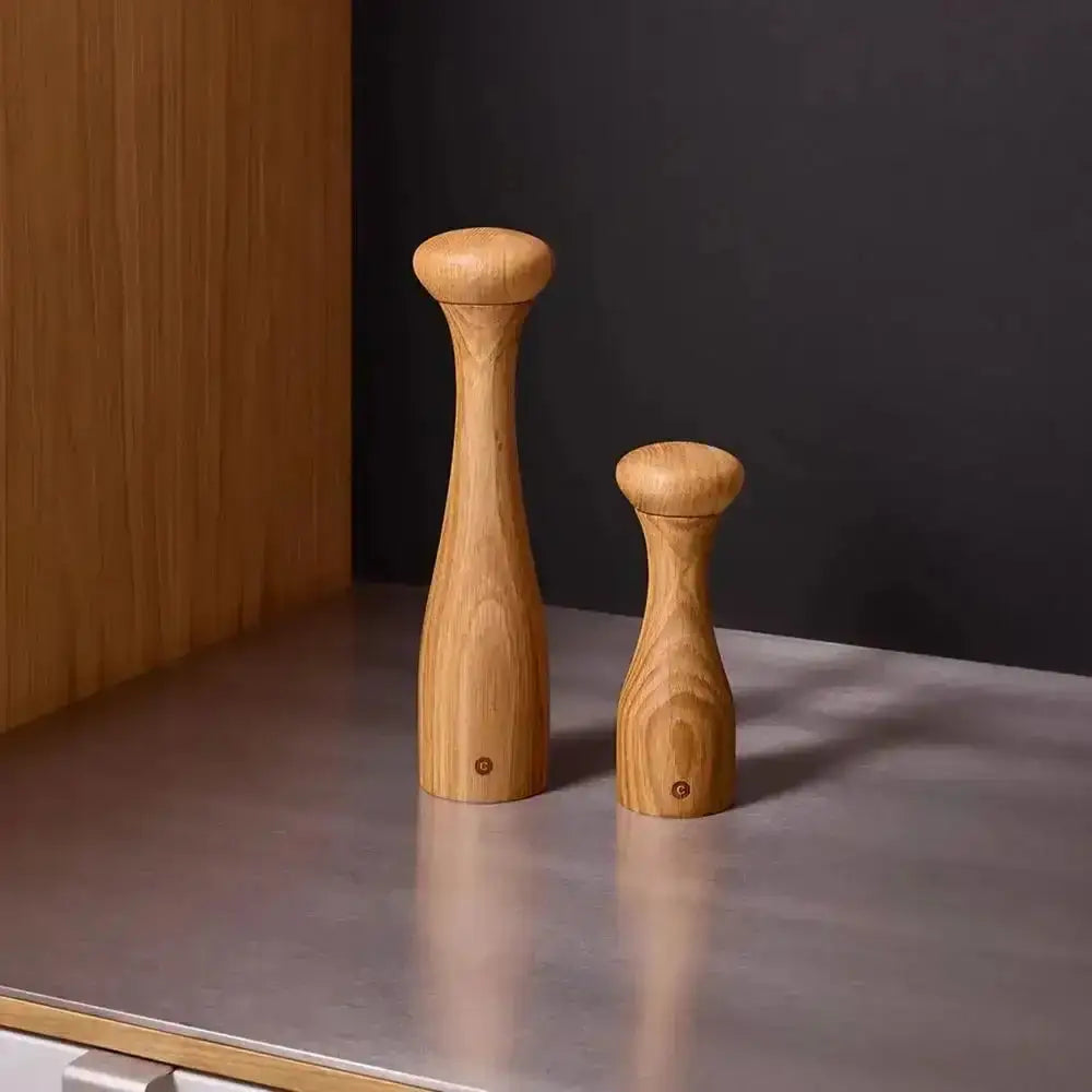 Oak wood salt and pepper grinders on a modern kitchen counter at Cookin Stores