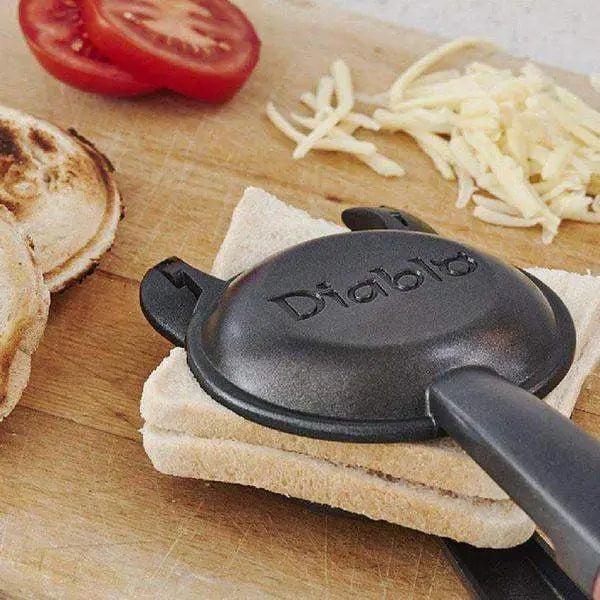 Diablo titanium non-stick jaffle iron pressing sandwich on wooden board with cheese and tomato, Cookin Stores kitchenware.