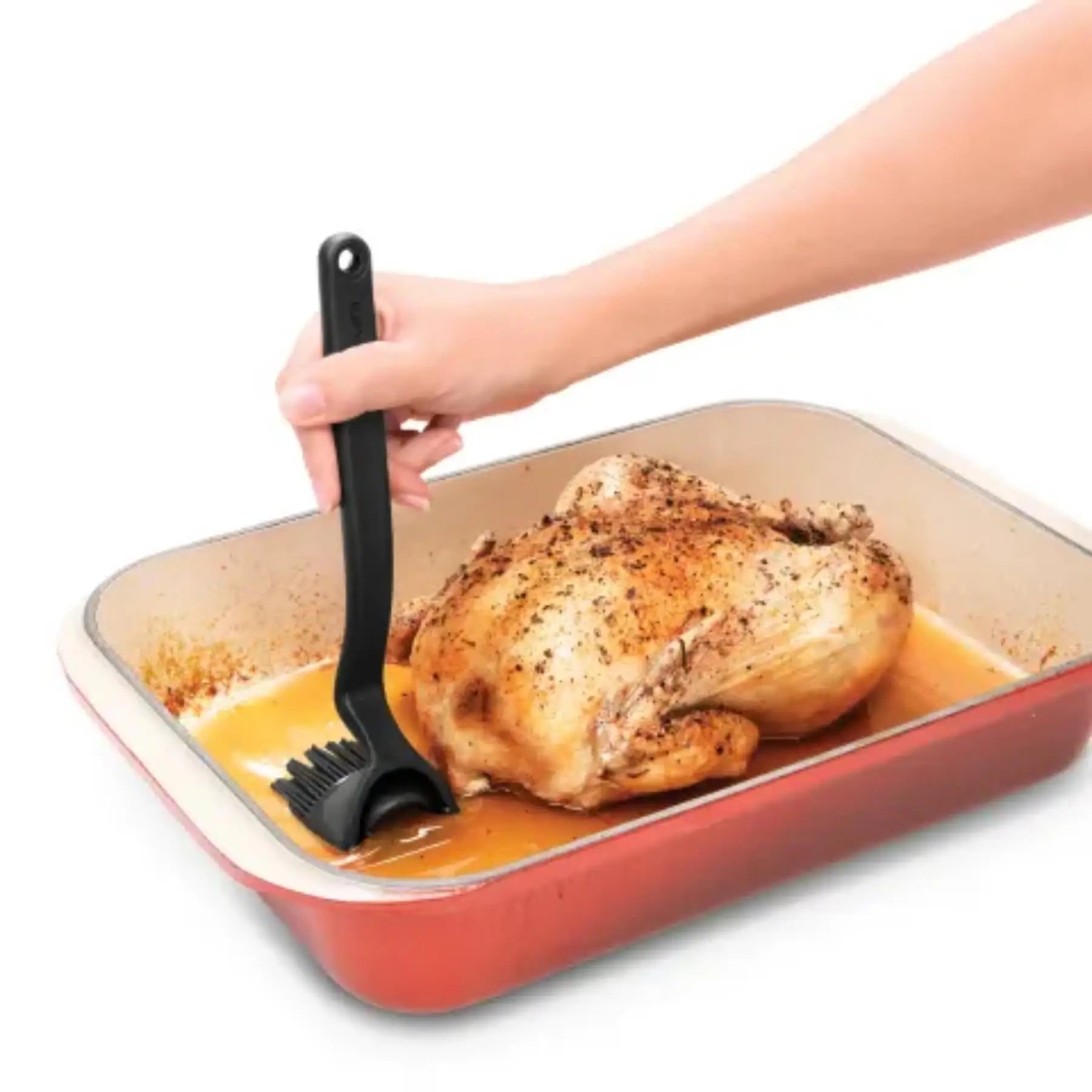 Dreamfarm bbq brizzle black silicone bristle basting brush with looped handle applying sauce to roasted chicken