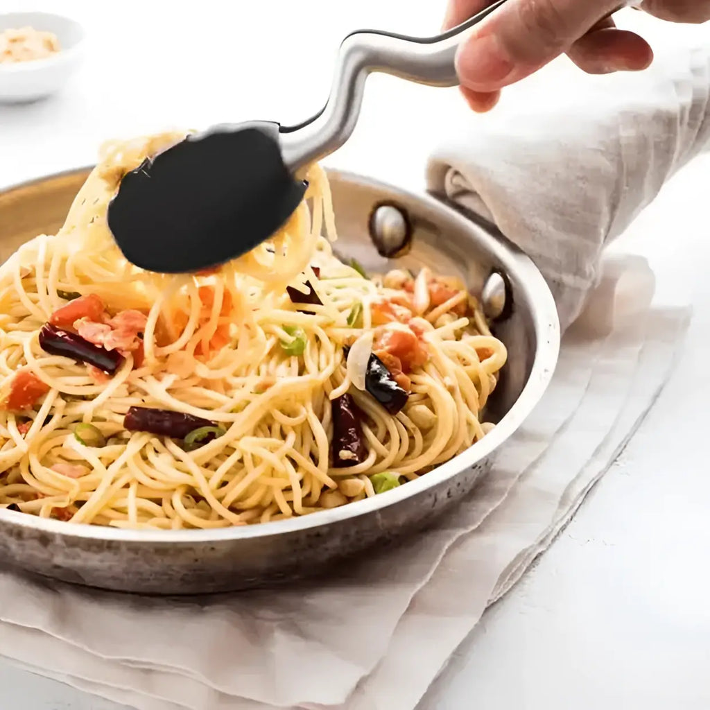Hand using a black spatula to serve spaghetti from a pan on a white background