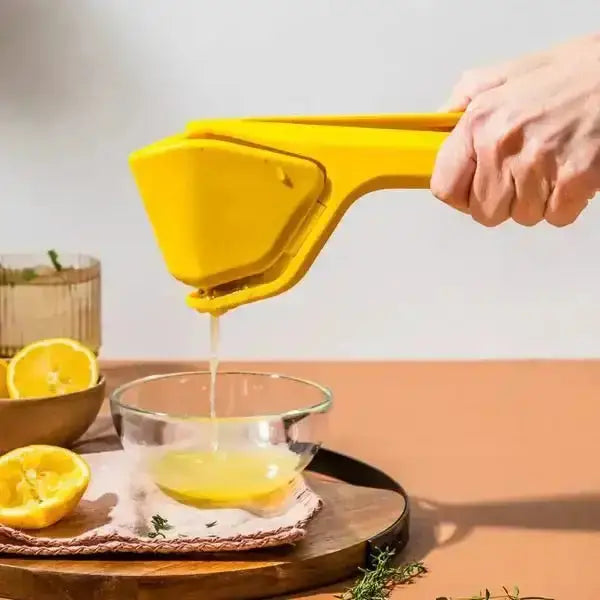 Hand using yellow lemon juicer to squeeze juice into glass bowl on kitchen counter