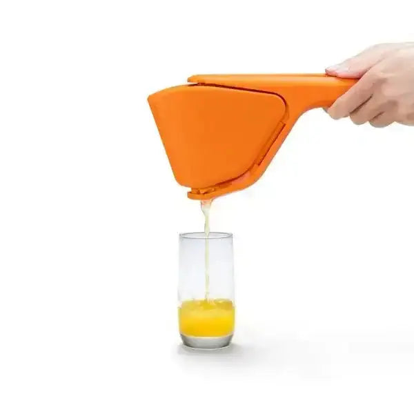 Hand using orange Dreamfarm Fluicer lemon squeezer over glass with fresh juice, Cookin Stores