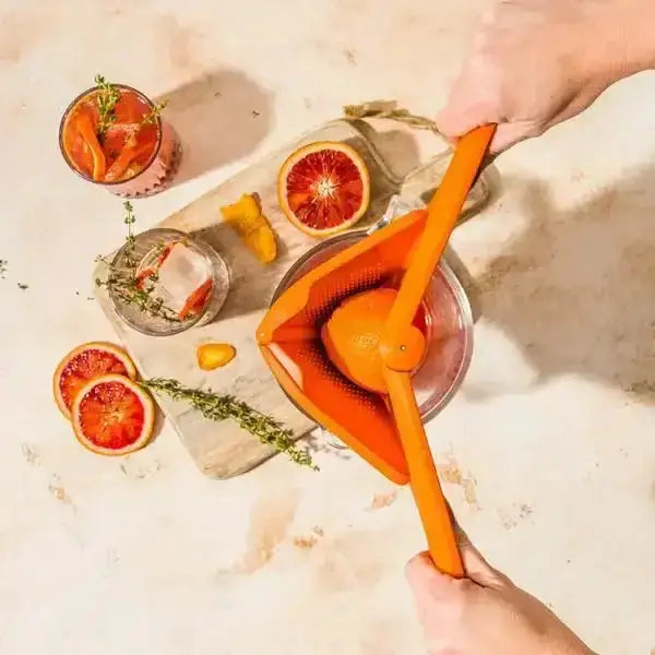 Dreamfarm Fluicer lemon squeezer juicing an orange on a kitchen counter with citrus drinks