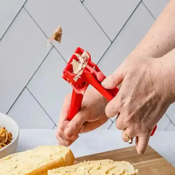 Red garlic press in use over bread on kitchen counter, kitchenware from Cookin Stores