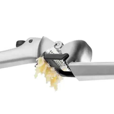 Garlic press with minced garlic on a white background