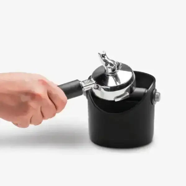 Hand using espresso portafilter with black Dreamfarm Grindstein coffee knock box, Cookin Stores kitchenware