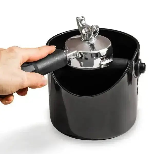 Black pot with a silver lid being held by a hand on a white background