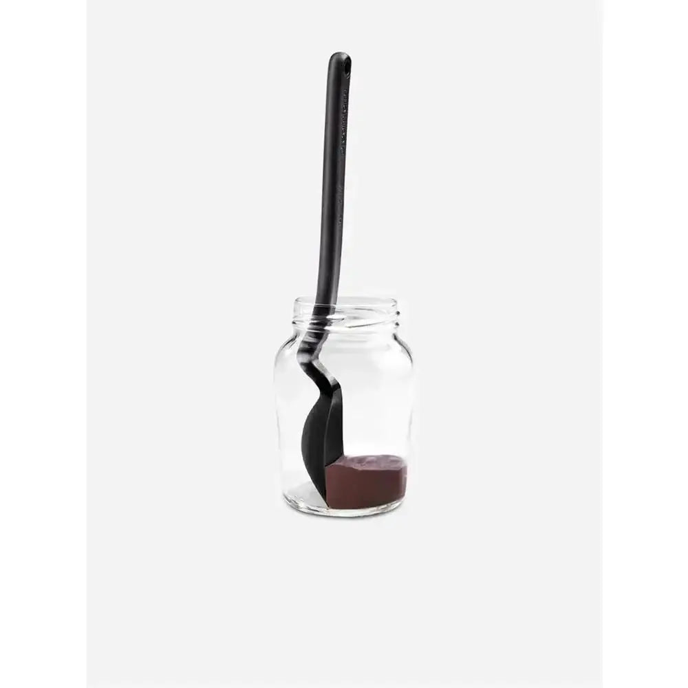 Glass jar with a black spoon inside on a white background