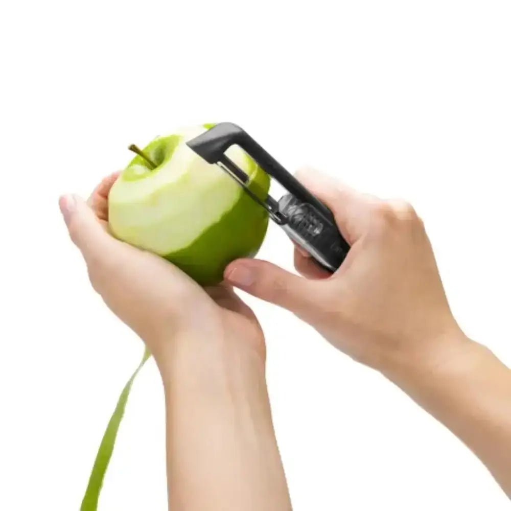 Person using an apple peeler on a green apple with a white background