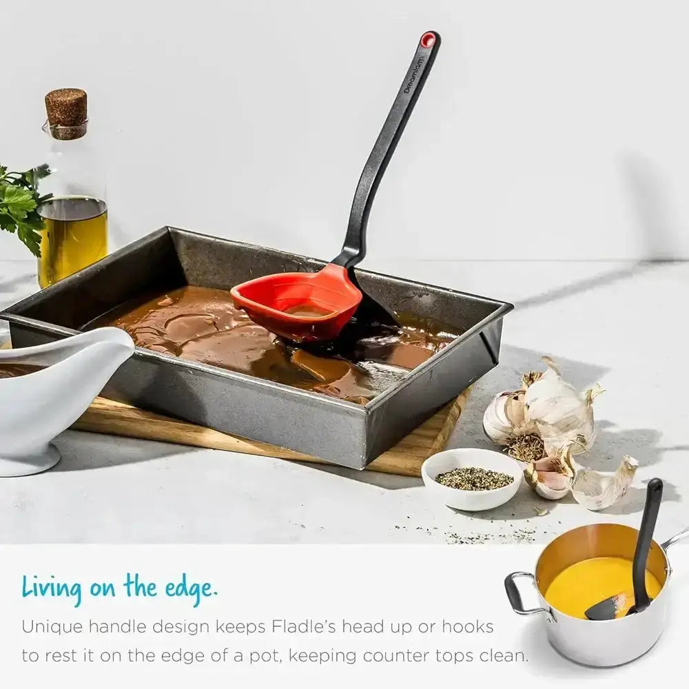 Cooking scene with a frying pan, spatula, and various kitchen items on a white surface.