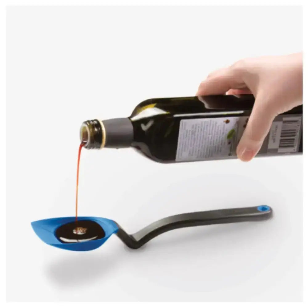 Hand pouring oil into a blue kitchen measuring spoon on white background