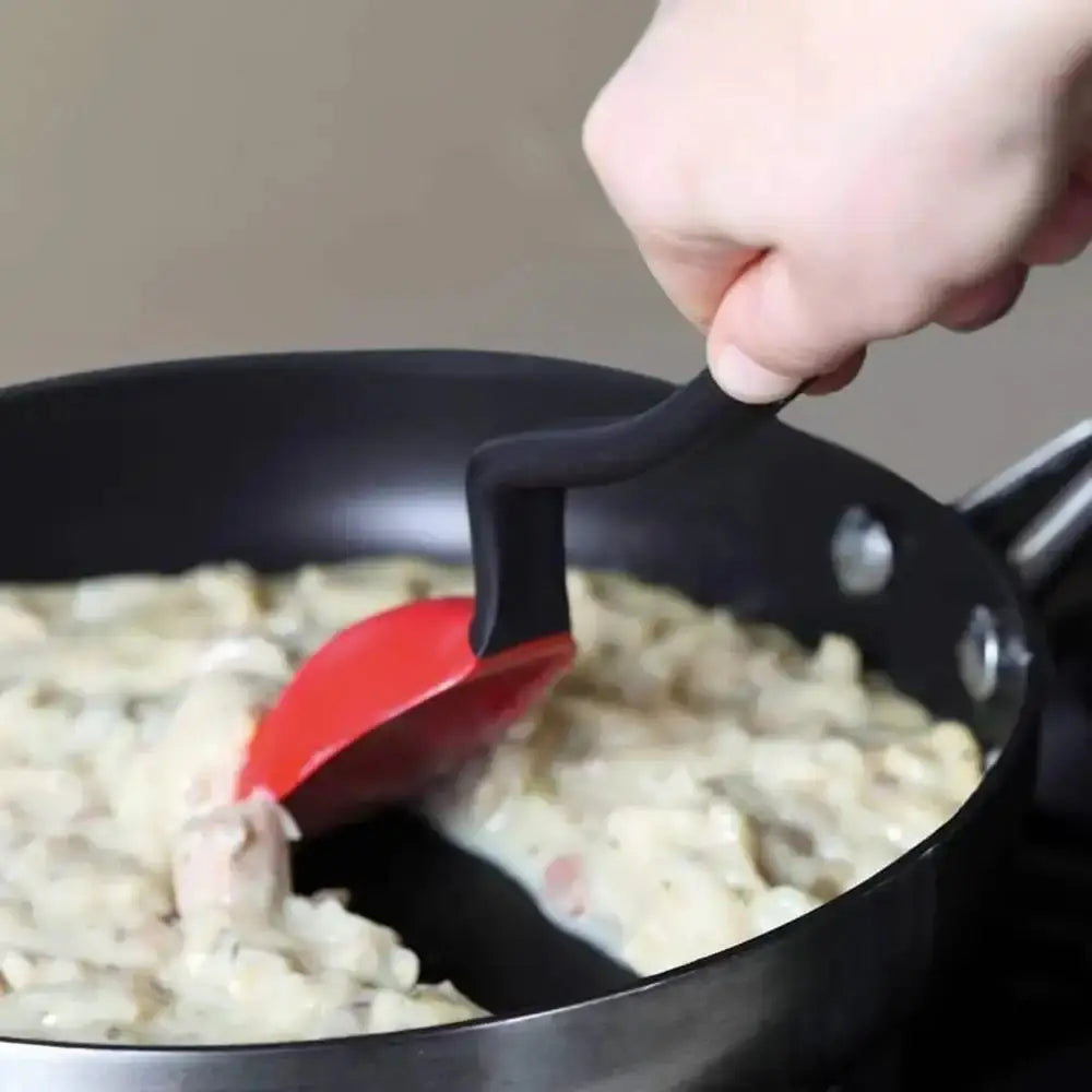 Person using a red spatula to stir food in a pan