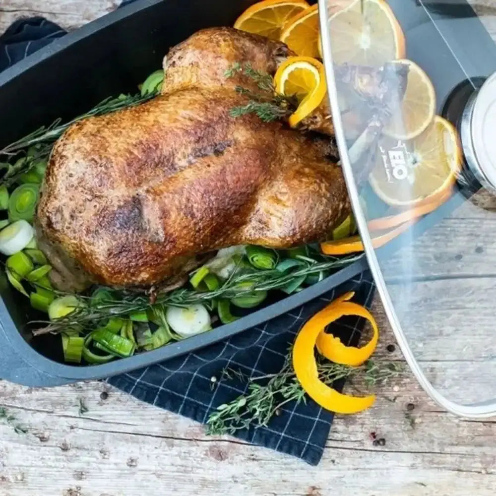 Roasted turkey with vegetables in a roasting pan on a wooden surface